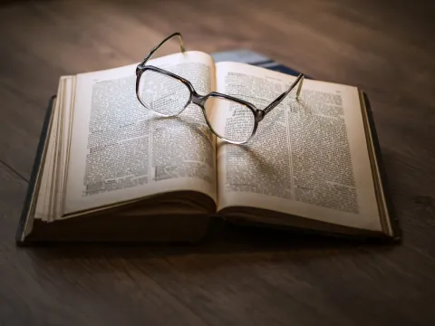 Reading glasses on the open pages of a book.