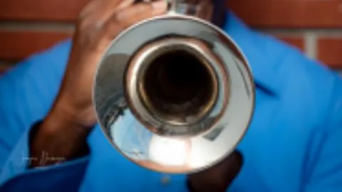 Looking at the bell of a trumpet being played by an African American man